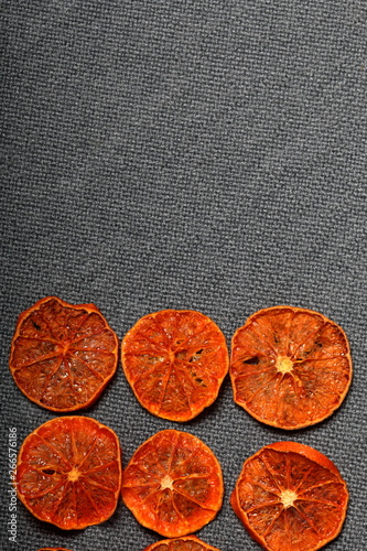 Tangerines are cut into slices and dried to decorate desserts. On a gray background.