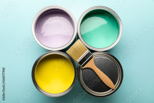 top view of tins of paints and brush on blue surface