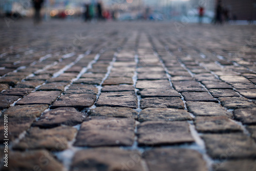 Stone pavement in perspective. Old street paved with stone blocks. Shallow depth of field. Vintage grunge texture.