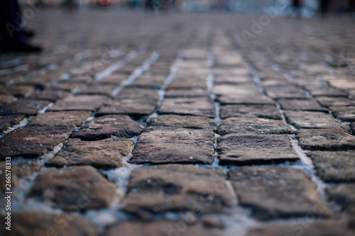 Stone pavement in perspective. Old street paved with stone blocks. Shallow depth of field. Vintage grunge texture.