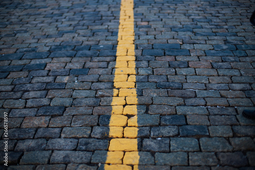 Stone pavement in perspective. Old street paved with stone blocks  with yellow line in the middle. Shallow depth of field. Vintage grunge texture. photo