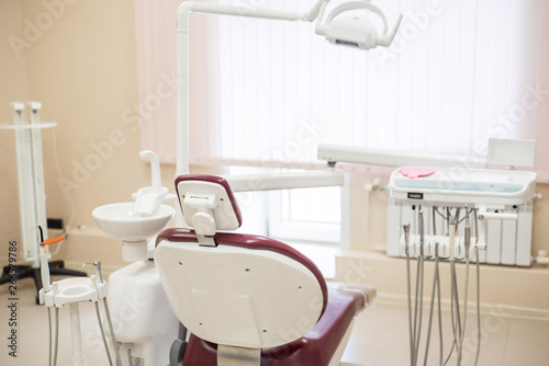 Empty dental chair in a bright medical office, rear view.