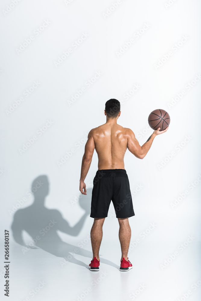 back view of athletic man in black shorts holding brown ball on white background back view of athletic man in black shorts holding brown ball on white background