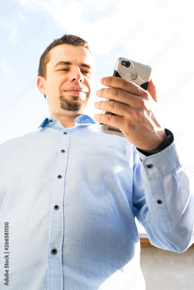 Young business man using cellphone laughing and typing message Young business man using cellphone laughing and typing message