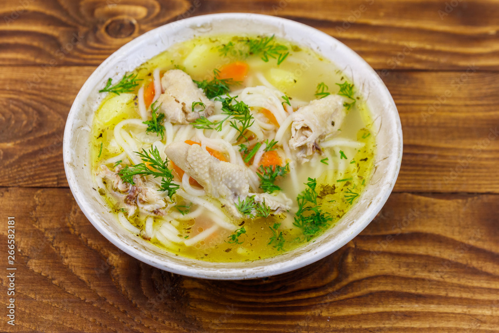 Chicken soup with noodles and vegetables on wooden table