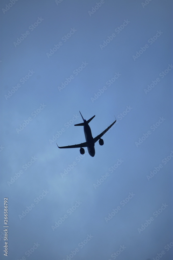 Aviation Industry - An air plane with tilted wings landing down posture in a cloudy dark blue background - Travel concept Aviation Industry - An air plane with tilted wings landing down posture in a cloudy dark blue background - Travel concept