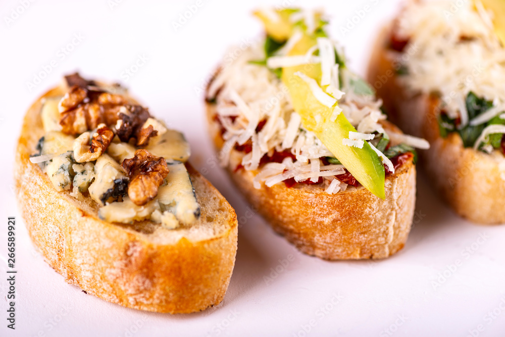 Set of assorted bruschetta with various toppings for holiday on white background. Close-up. Party food concept. Set of assorted bruschetta with various toppings for holiday on white background. Close-up. Party food concept.