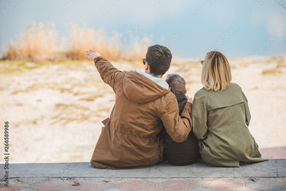 Fototapeta premium young beautiful family sitting at beach with view lake