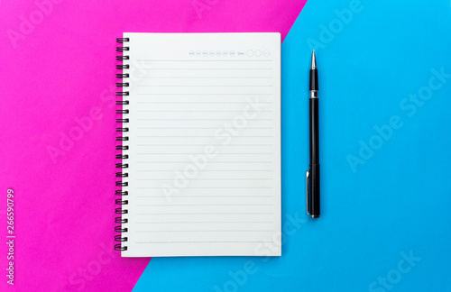 Top view blank notebook and black pen for mockup flat lay on blue and pink background.