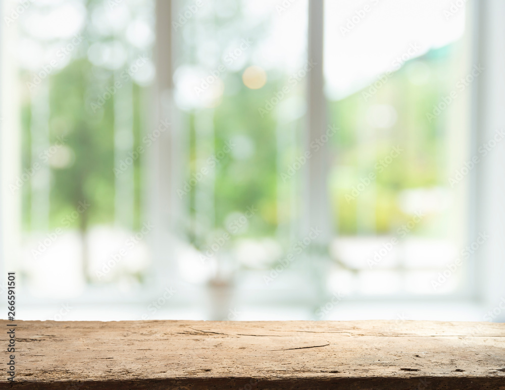 Wood table top on blur of window glass and abstract green from garden with city view in the morning background. For montage product display