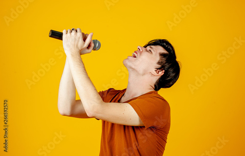 Karaoke man singing a song into a microphone, on a yellow background. A funny man holds a microphone in his hand at the karaoke singer singing a song! Pivets on a yellow background