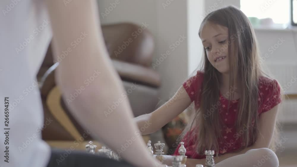 Portrait unrecognizable father and little girl playing chess sitting on the floor close up. The daughter wins, she is excited and happy, people high five. Family leisure. Fatherhood, childhood Portrait unrecognizable father and little girl playing chess sitting on the floor close up. The daughter wins, she is excited and happy, people high five. Family leisure. Fatherhood, childhood
