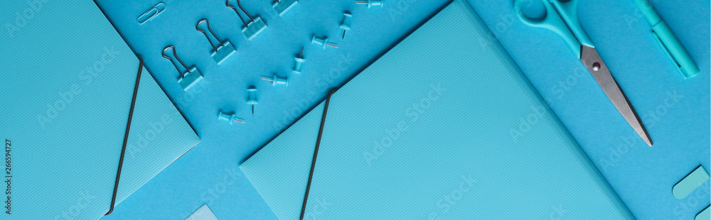 panoramic shot of paper binders and various stationery isolated on blue panoramic shot of paper binders and various stationery isolated on blue
