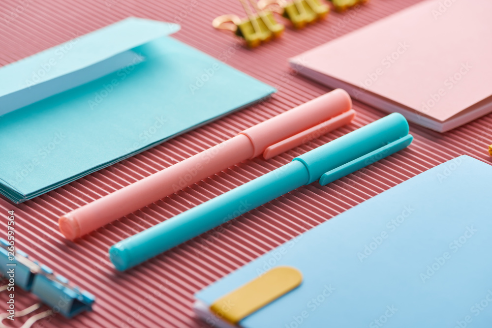 close up of pens and colorful notebooks on pink close up of pens and colorful notebooks on pink