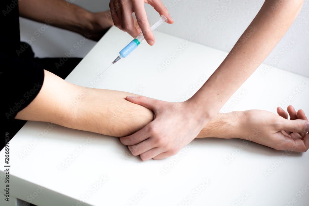 Nurse doing an injection to the patient of a medical clinic. Doing anesthesia before a surgery. Hands syringe close-up. Nurse doing an injection to the patient of a medical clinic. Doing anesthesia before a surgery. Hands syringe close-up.