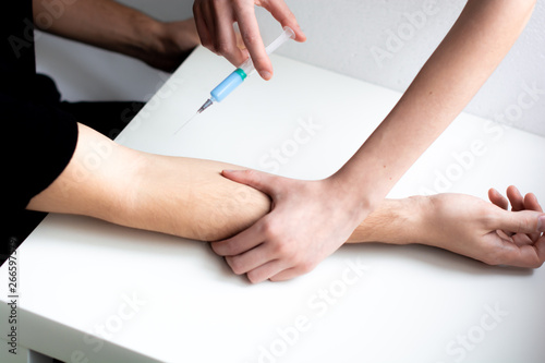 Nurse doing an injection to the patient of a medical clinic. Doing anesthesia before a surgery. Hands syringe close-up.