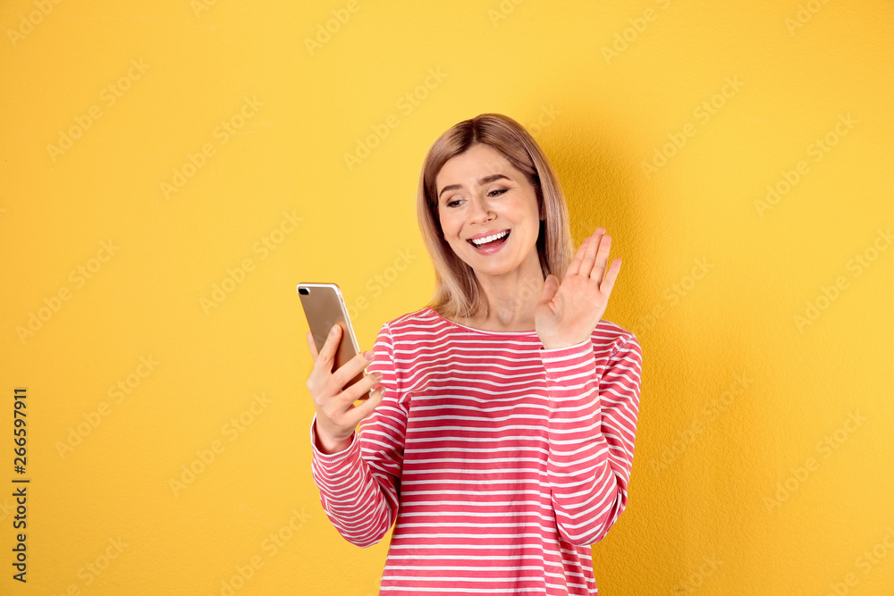 Woman using mobile phone for video chat on color background Woman using mobile phone for video chat on color background