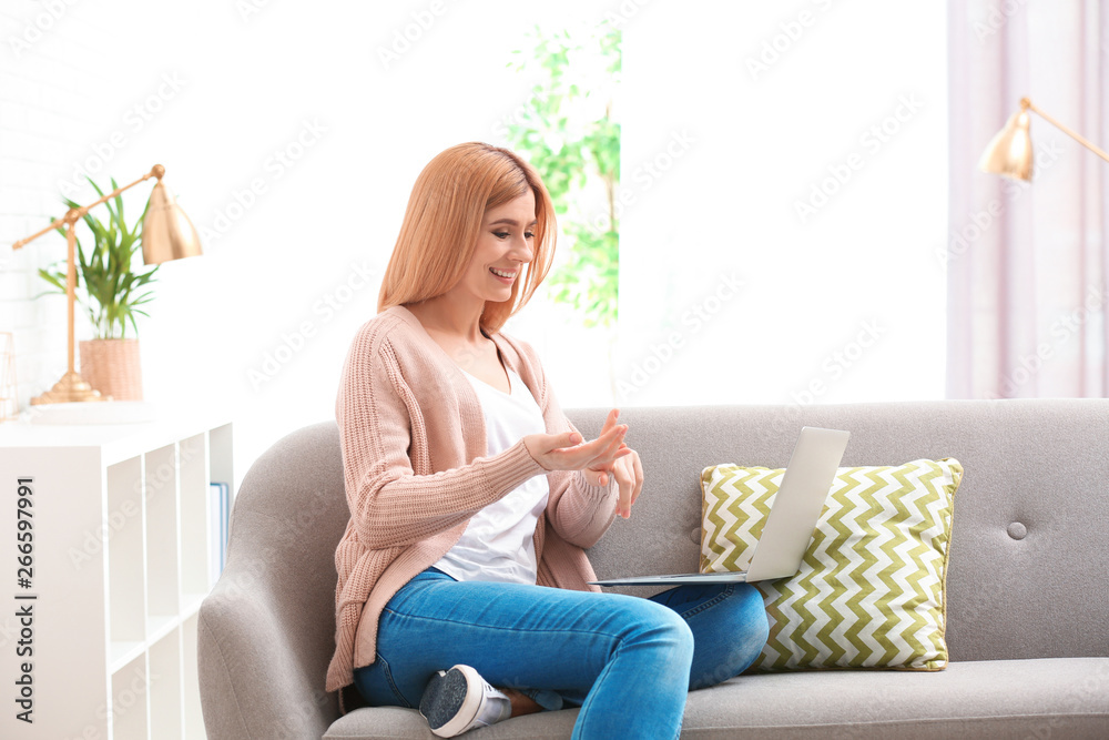 Woman using laptop for video chat in living room Woman using laptop for video chat in living room
