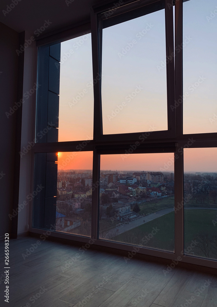 Fototapeta premium Panoramic windows overlooking beautiful golden sunset. View from home window