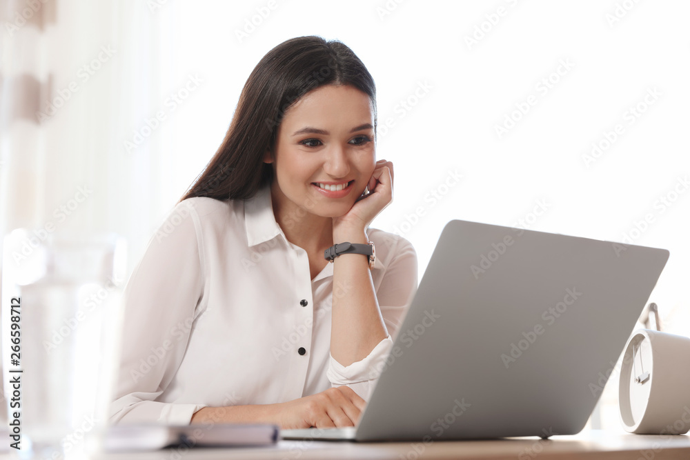 Young woman using video chat on laptop in home office Young woman using video chat on laptop in home office