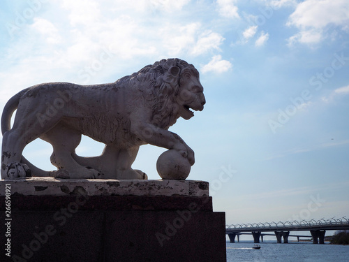 Sculpture of white stone lion on the river bank in The Kirov Central Park on Elagin Island in Saint-Petersburg, Russia