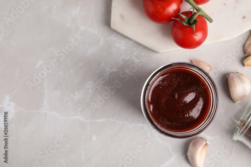 Flat lay composition with jar of barbecue sauce on grey background. Space for text