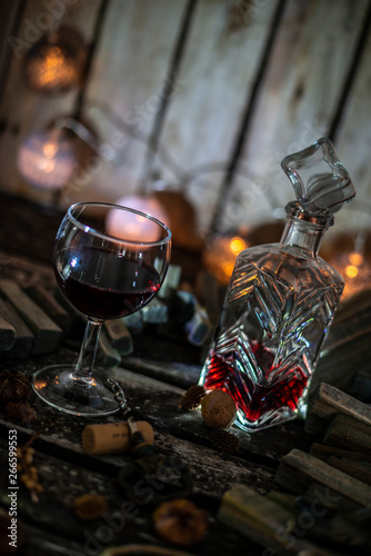 Fototapeta Naklejka Na Ścianę i Meble -  Red wine on a wooden table in front of a wooden background with a creative lighting