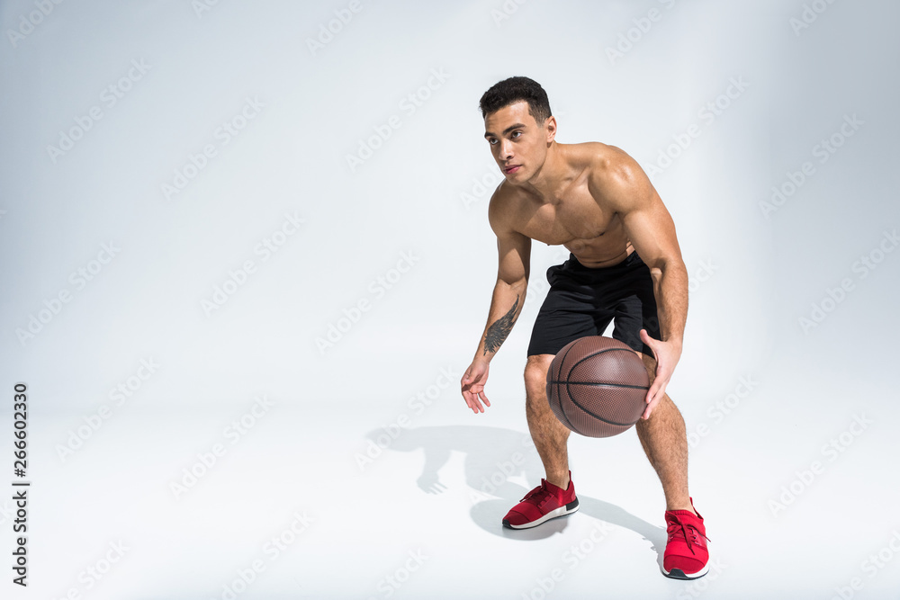 handsome sportive mixed race man in red sneakers playing ball on white handsome sportive mixed race man in red sneakers playing ball on white