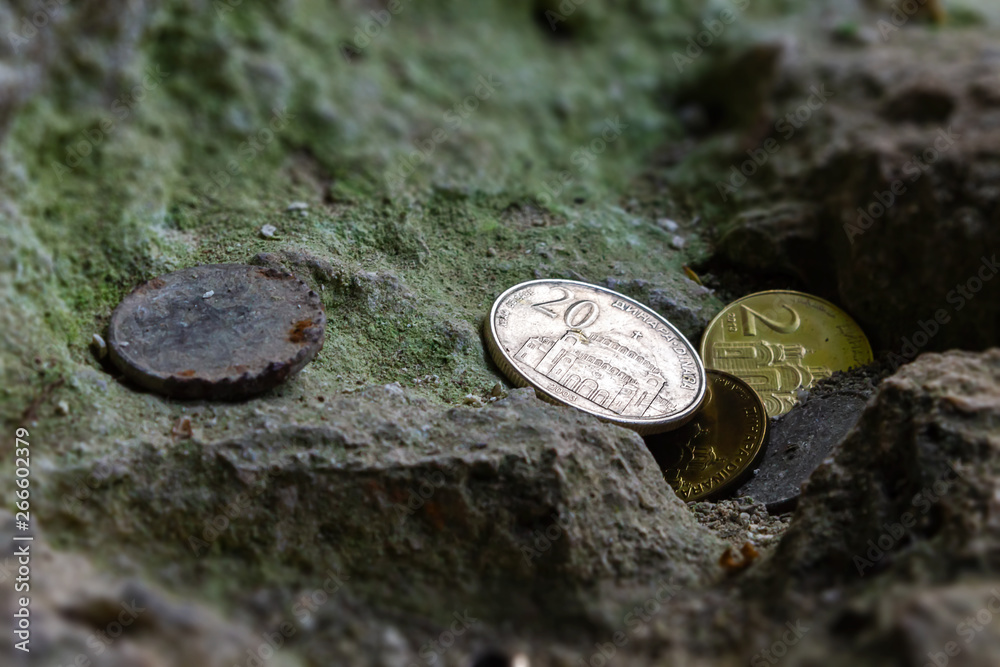 Several Serbian, new and old corroded coins were left near a religious object on a moss stone Several Serbian, new and old corroded coins were left near a religious object on a moss stone