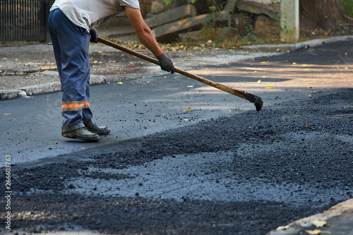 Worker operating the process of building new asphalt road on the new road construction