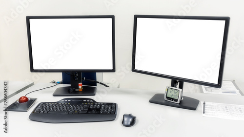 Two computer monitors are on the table in the office. On the monitors white screen to insert images or text