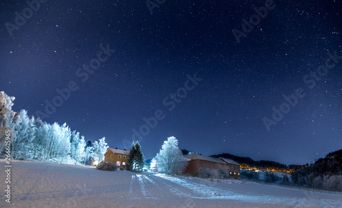 Single house and night lights with starry sky.