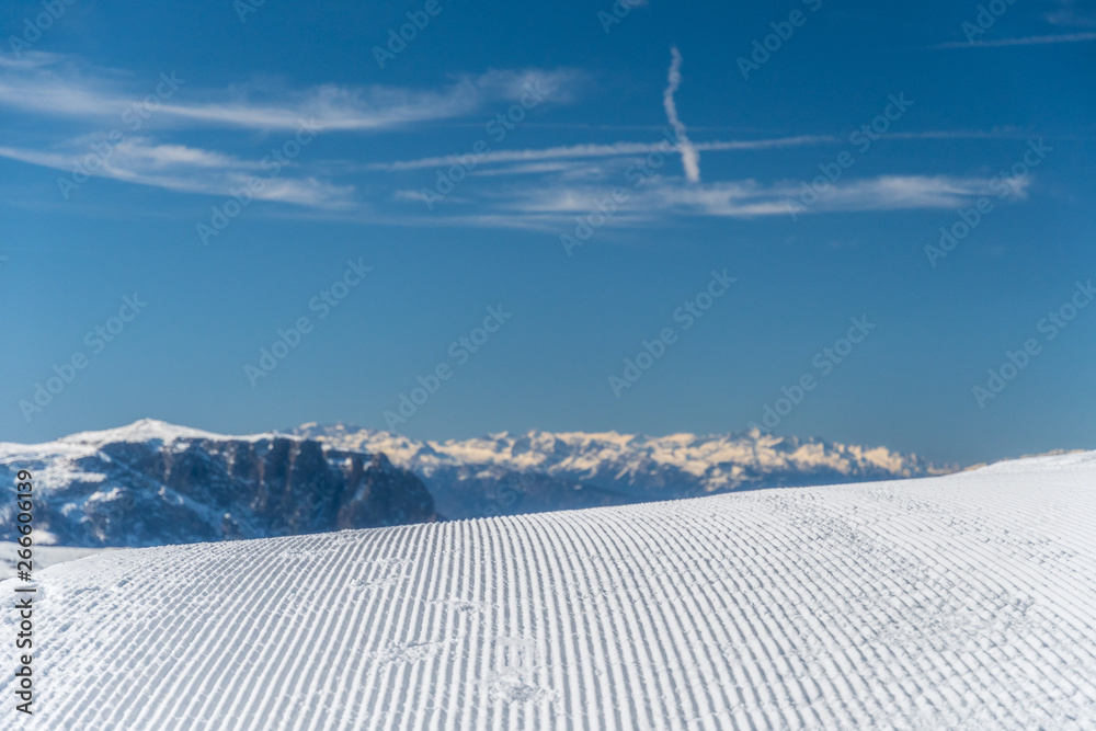 Panorama of Dolomites Alps, Val Gardena, Italy with groomed piste in the foreground