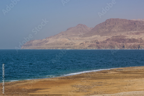 sand beach of dead sea Middle East scenery landscape place with view on gulf and slightly foggy mountains background