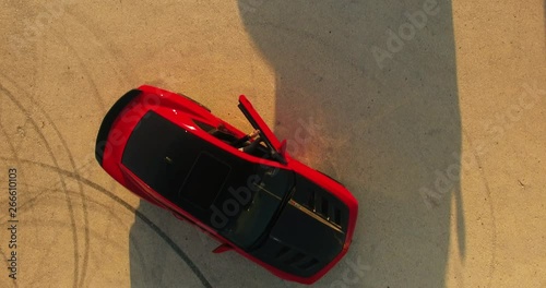 An aerial bird eye following shot of a man walking to a red car An aerial shot of a man walking toward his red race sport red car and open door and getting in photo