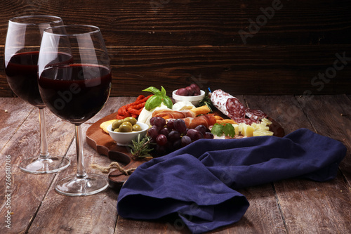 antipasto various appetizer. Cutting board with prosciutto, salami, cheese, bread and olives on dark wooden background
