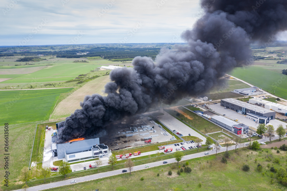 Aerial view of burnt industrial warehouse or logistics center building after big fire with huge smoke from burned roof