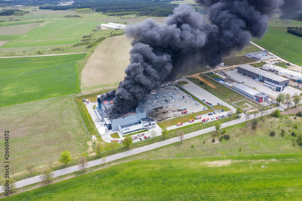 Aerial view of burnt industrial warehouse or logistics center building after big fire with huge smoke from burned roof