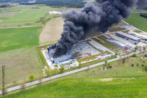 Obraz na płótnie Aerial view of burnt industrial warehouse or logistics center building after big fire with huge smoke from burned roof w salonie