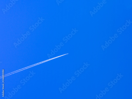 airplane contrail against clear blue sky with copy space