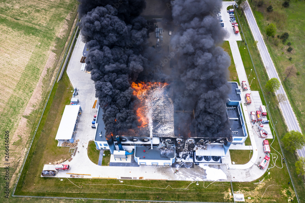 Aerial view of burnt industrial warehouse or logistics center building after big fire with huge smoke from burned roof
