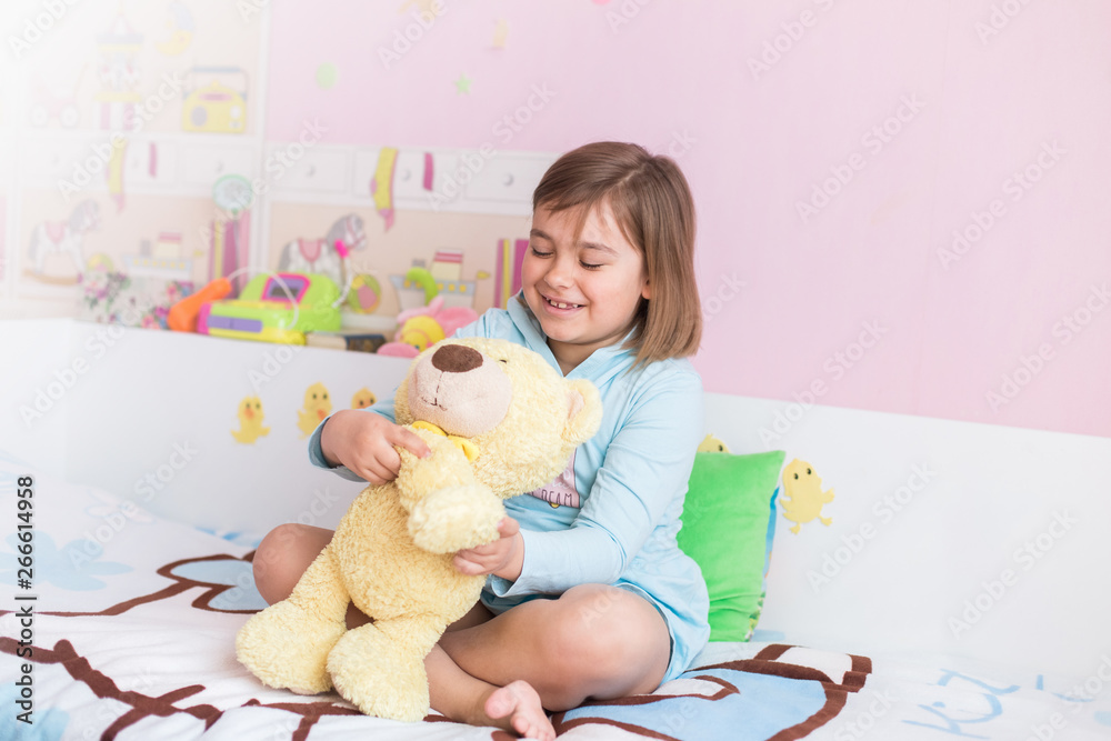 Cheerful little cute adorable baby girl playing with yellow teddy bear in her children room. Childhood, leisure kid time, happiness concept Cheerful little cute adorable baby girl playing with yellow teddy bear in her children room. Childhood, leisure kid time, happiness concept