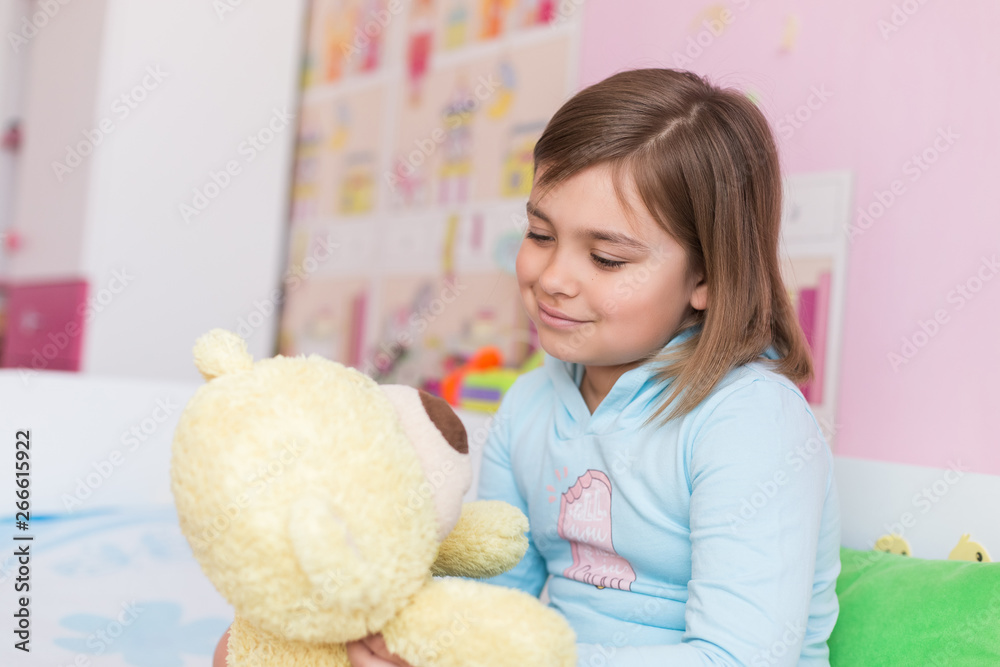 Cheerful little cute adorable baby girl playing with yellow teddy bear in her children room. Childhood, leisure kid time, happiness concept Cheerful little cute adorable baby girl playing with yellow teddy bear in her children room. Childhood, leisure kid time, happiness concept