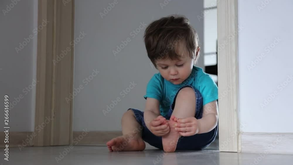 Little toddler boy sitting on a floor and play with his foots. Little toddler boy sitting on a floor and play with his foots.