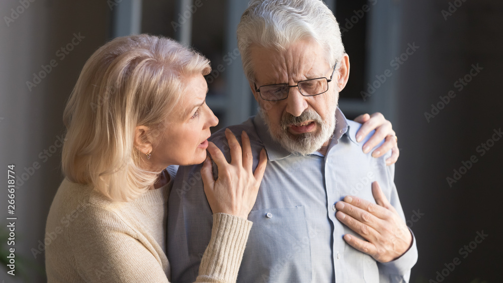 Grey haired man touching chest, having heart attack, woman supporting - obrazy, fototapety, plakaty 
