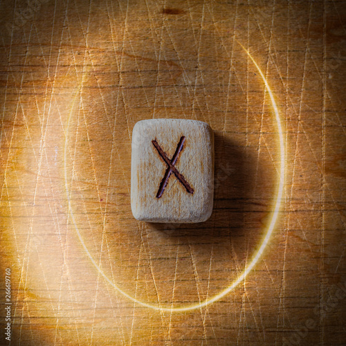 Gebo. Handmade scandinavian wooden runes on a wooden vintage background in a circle of light. Concept of fortune telling and prediction of the future.