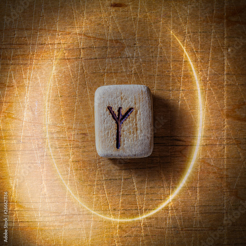 Algiz. Handmade scandinavian wooden runes on a wooden vintage background in a circle of light. Concept of fortune telling and prediction of the future.