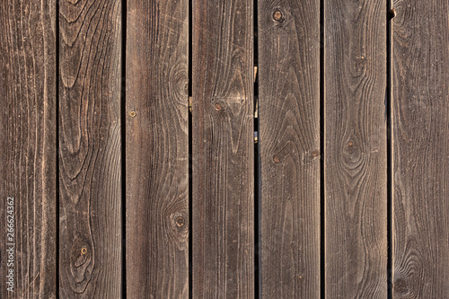 The fence is made of flat wooden planks. Empty background with texture of brown boards. Photo for the layout.