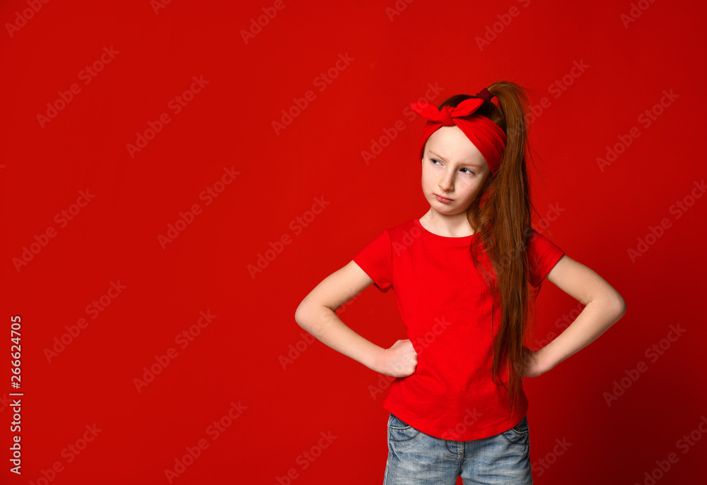 Cute little red-haired girl sulking and frowning while holding hands on the waist, offended and disappointed Cute little red-haired girl sulking and frowning while holding hands on the waist, offended and disappointed