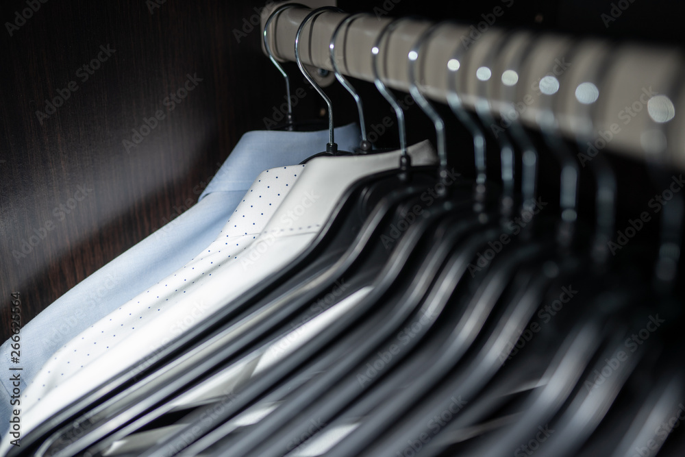 Neat blouse in a mens wardrobe / closet with clothes hangers Neat blouse in a mens wardrobe / closet with clothes hangers